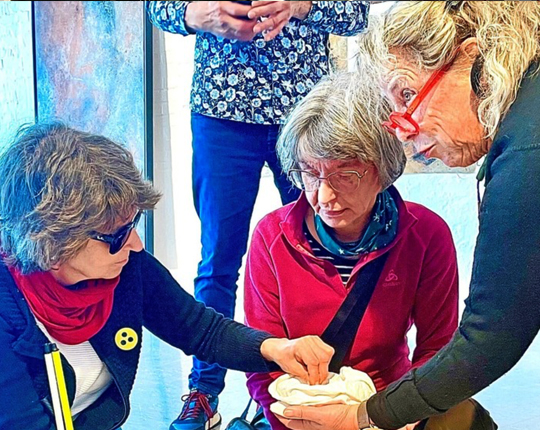 Künstlerin Ulrike Arnold hält Manuela Dolf und Gesine Wächter ein Ausstellungsstück hin, das sie ertasten konnten